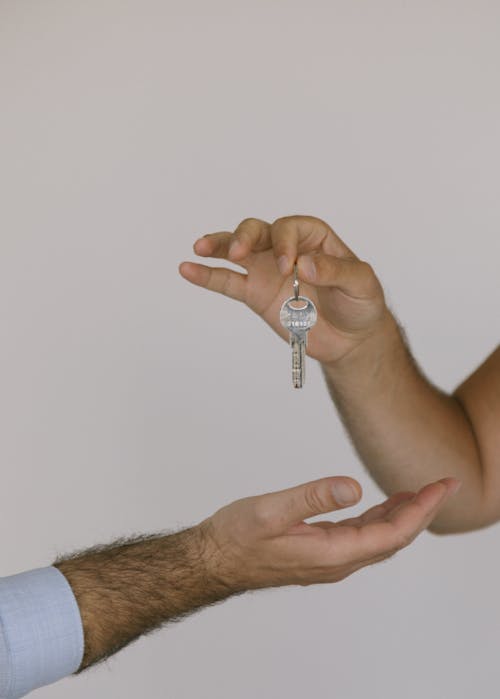 A Person Handing a Key to Another Person