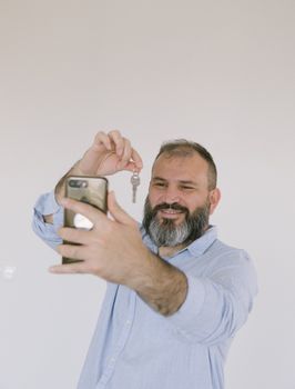 Bearded man inside taking a selfie while holding a key, expressing excitement.