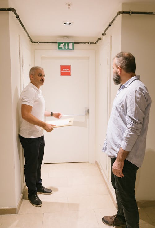 Man in White T-shirt and Black Pants Holding White Printer Paper