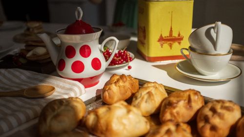 Free Charming image of a cozy table with baked goods, ornate teapot, and teacups on a wooden tray. Stock Photo