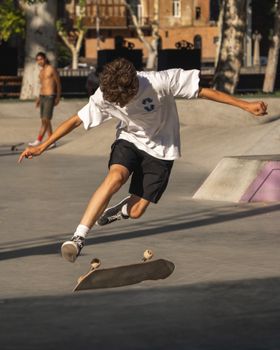 Young skateboarder mid-trick in a sunlit urban skatepark, showcasing skill and balance.