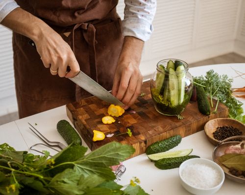 Free Person slicing vegetables on a wooden chopping board, showcasing fresh ingredients for a healthy meal. Stock Photo