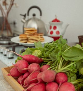 A close-up of fresh radishes on a kitchen counter with pancakes in the background.
