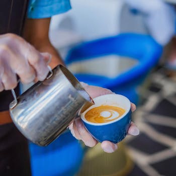 Close-up of a barista creating latte art in a blue cup with precision pouring technique.