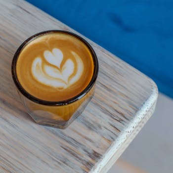 Close-up of a latte with intricate art served on a rustic wooden table, perfect for coffee lovers.