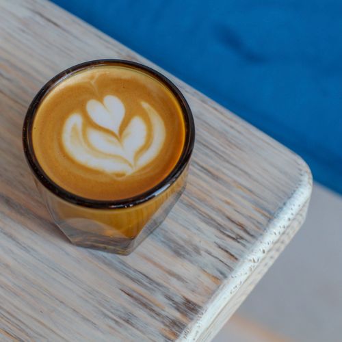 Free Close-up of a latte with intricate art served on a rustic wooden table, perfect for coffee lovers. Stock Photo