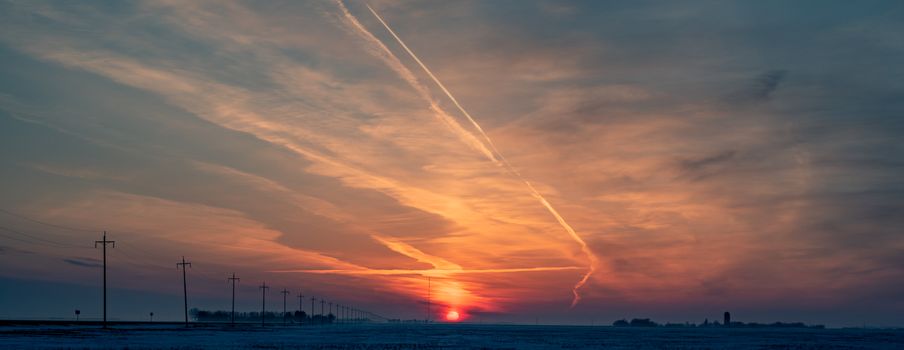 Captivating image of a sunset over a flat landscape with power lines.