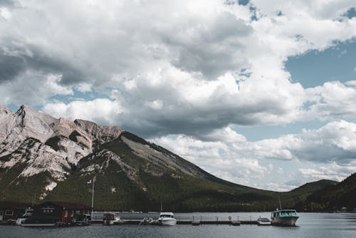 Boats on Dock Near Mountain Under White Clouds