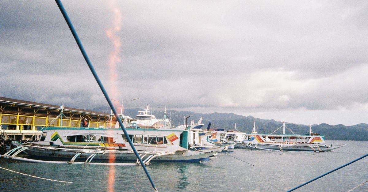 Traditional boats docked in Malay, Philippines under a cloudy sky. Ideal for travel enthusiasts.