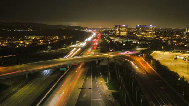 Aerial view of a bustling city highway at night, showcasing vibrant lights and urban architecture.