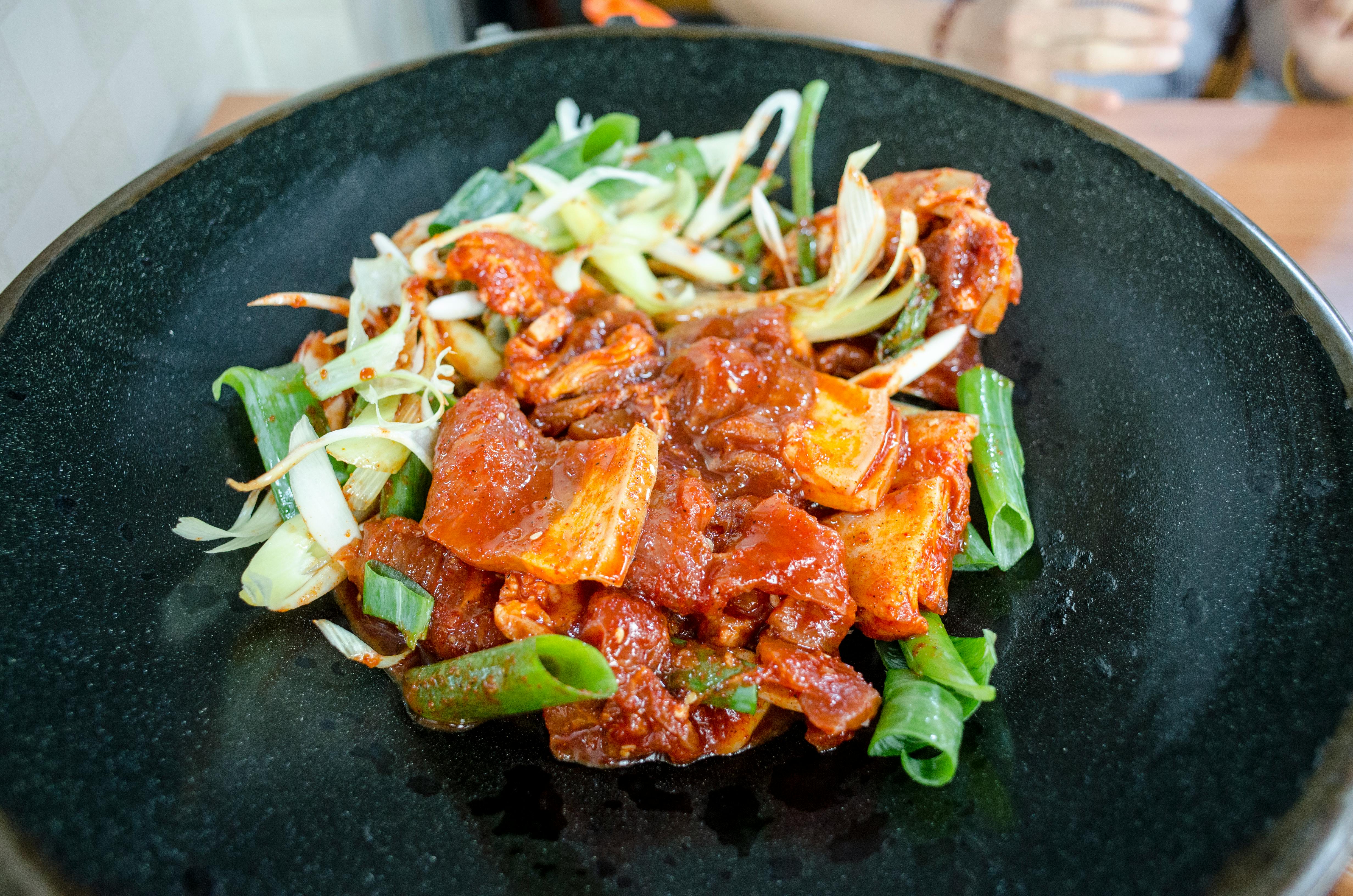 Free A close-up of spicy kimchi and vegetables on a black plate, perfect for food enthusiasts. Stock Photo