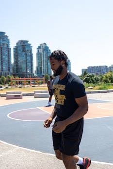 An African American man plays basketball on an outdoor court in the city.