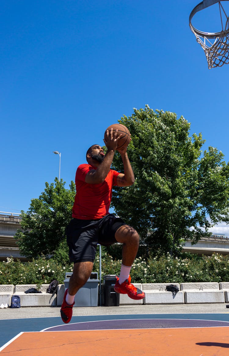 A Man In Red Shirt Playing Basketball