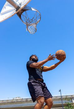 Energetic outdoor basketball game with an adult man jumping to score.