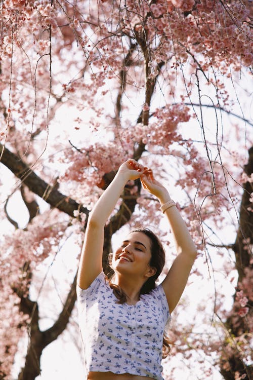Free Woman Under the Cherry Blossom Tree Raising her Arms  Stock Photo