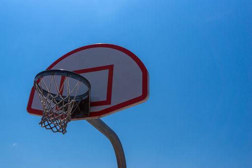 Free Low-angle shot of a basketball hoop against a clear blue sky, showcasing sports and outdoor activities. Stock Photo