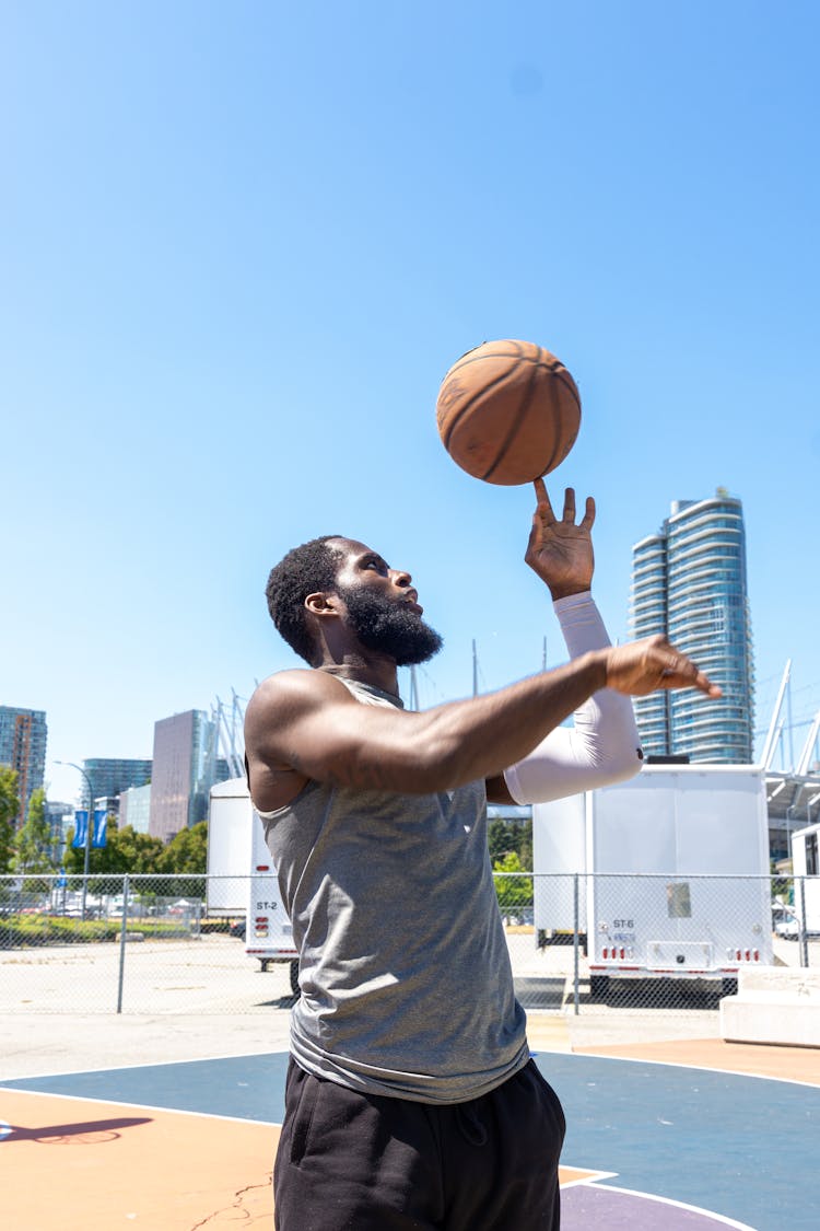 Man In Gray Shirt Spinning A Basketball On His Finger