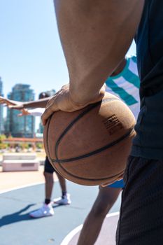 Close-up of men playing basketball on a vibrant outdoor court in the city.