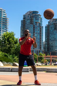 African American man playing basketball outdoors in a city, showcasing athleticism.