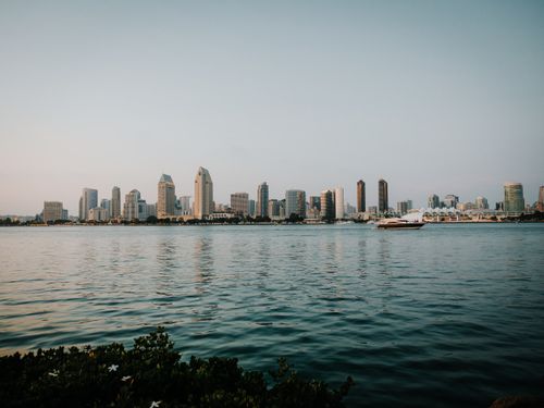 Free Panoramic view of San Diego skyline reflecting on the bay with a yacht cruising by. Stock Photo