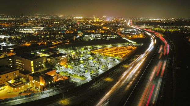 Aerial view of a bustling cityscape with illuminated highways and buildings at night.