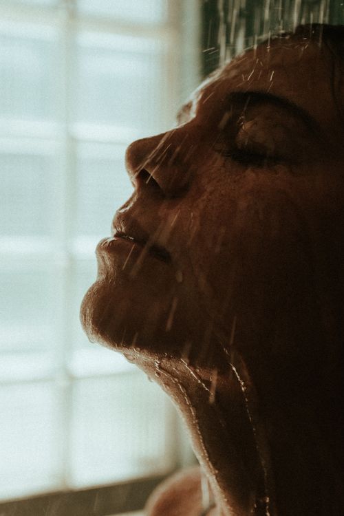 Free Intimate close-up of a person relaxing under a shower with warm tones. Stock Photo