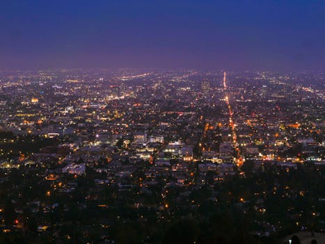 Vibrant city lights and urban sprawl photographed from above during nighttime, showcasing a bustling modern city.