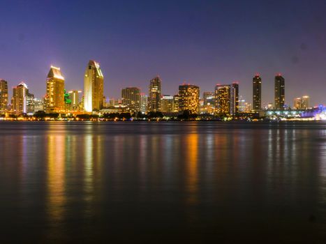 Stunning night view of San Diego's illuminated skyline with calm waterfront reflections.