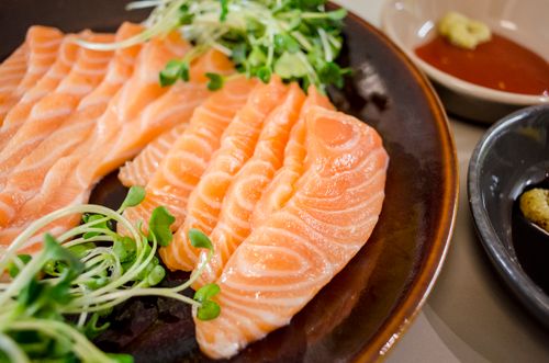 Free Delicious salmon sashimi served with fresh greens and dipping sauces on a plate. Stock Photo