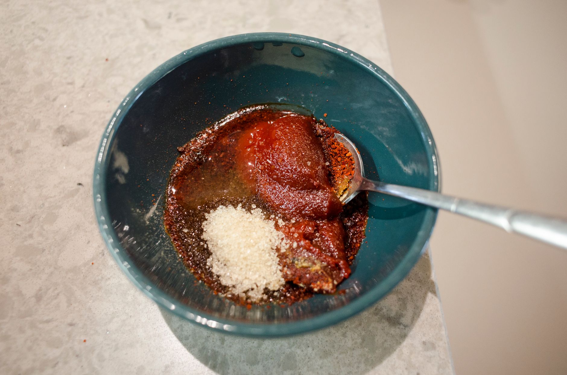 Close-up of spices and seasoning in a bowl with a spoon, ready for mixing.
