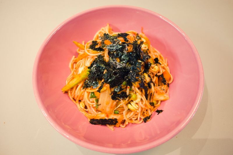 Close-up of spicy Korean noodles with bean sprouts and nori on a plate