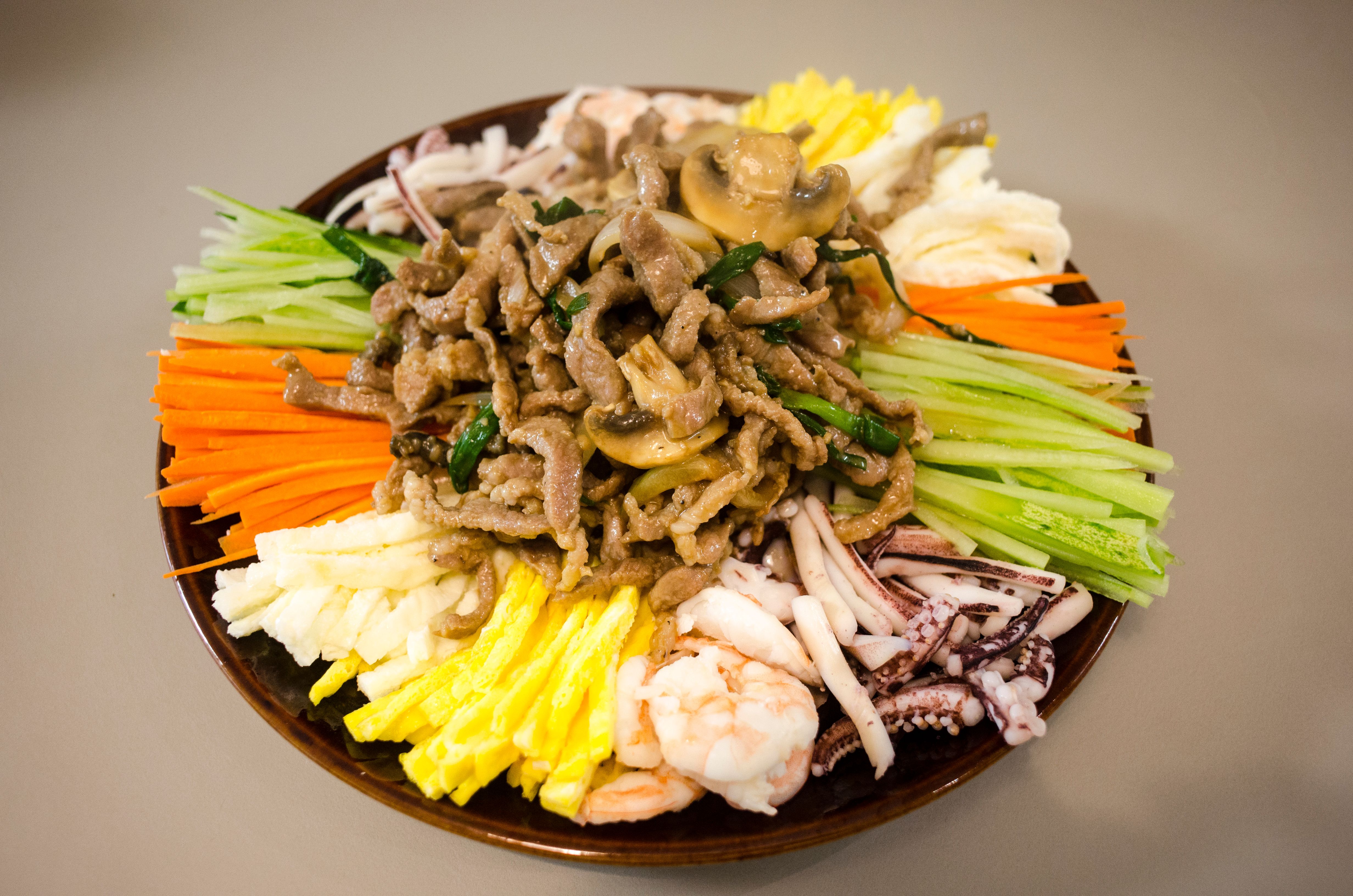 A vibrant Asian dish showcasing seafood, vegetables, and meats artistically arranged on a plate.
