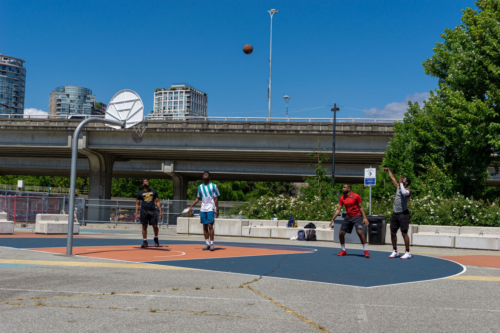 Grupo de amigos jogando basquete em quadra de rua embaixo de um viaduto na cidade