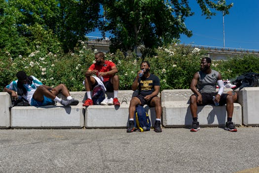 Four men sitting and chatting on a concrete bench under sunny skies.
