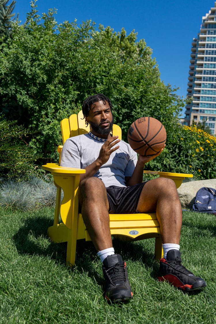 Man Sitting On A Yellow Chair Holding Basketball