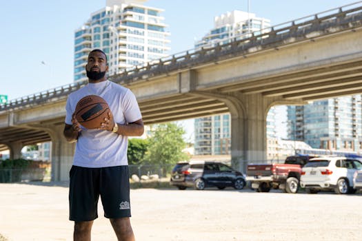 Man in city setting holding basketball under bridge, ready to play.