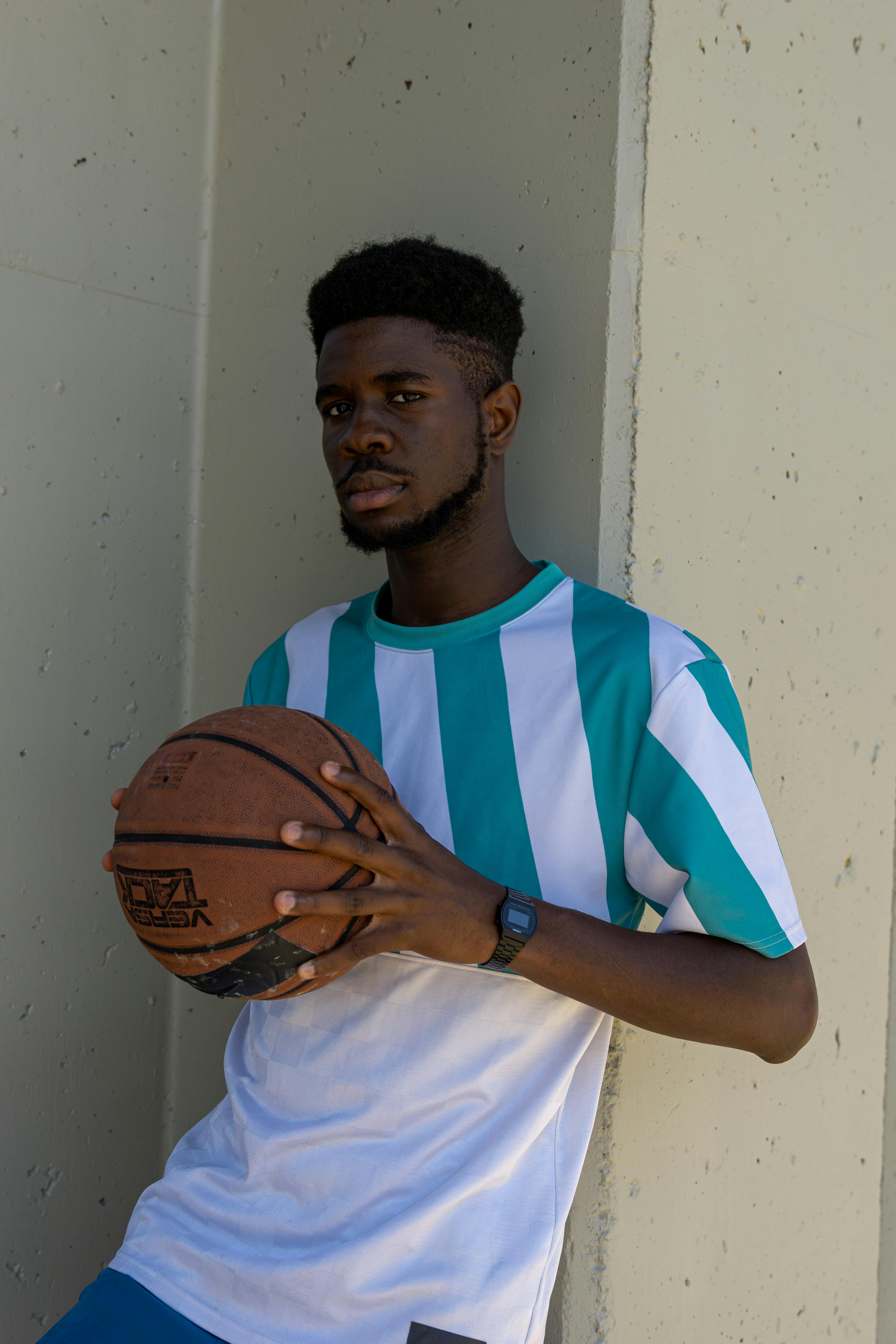 a man leaning on the wall while holding a ball