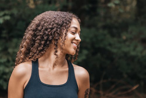 Smiling Woman in Black Tank Top With Curly Hair