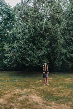 Two women stand in a grass field surrounded by trees, meditating outdoors.