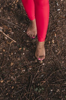 Close-up of bare feet walking on soil and twigs, showcasing earthy connection.
