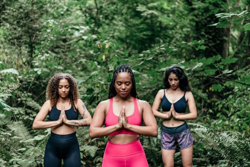 Free Women Wearing Sports Bra Meditating in the Woods Stock Photo