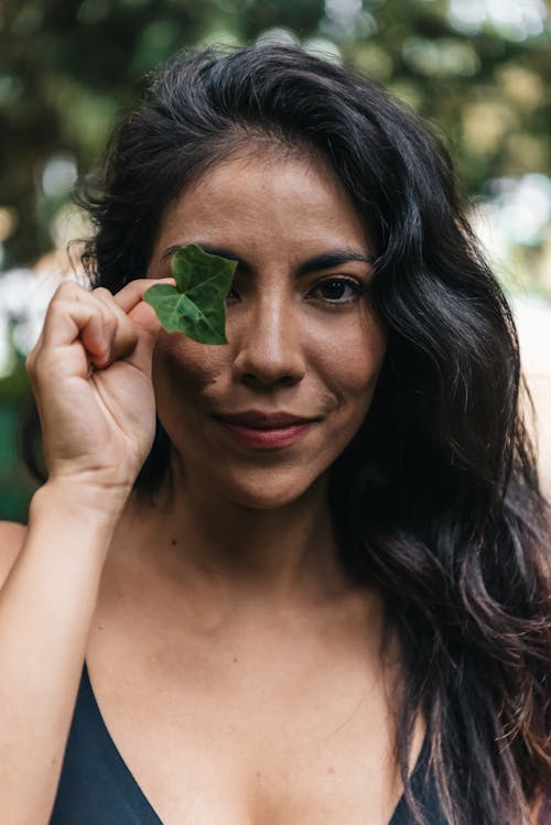 Woman Holding a Green Leaf Covering Her Eye