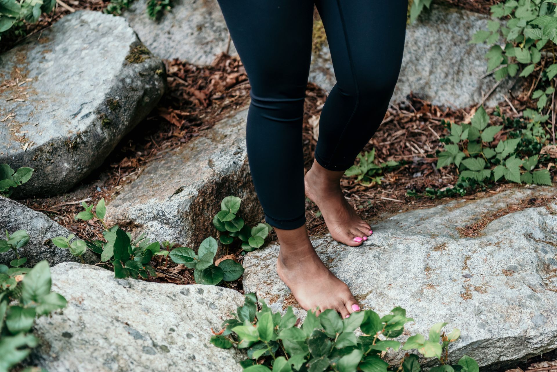 Person standing barefoot on natural rocks, connecting with nature, emphasizing grounding and mindfulness.