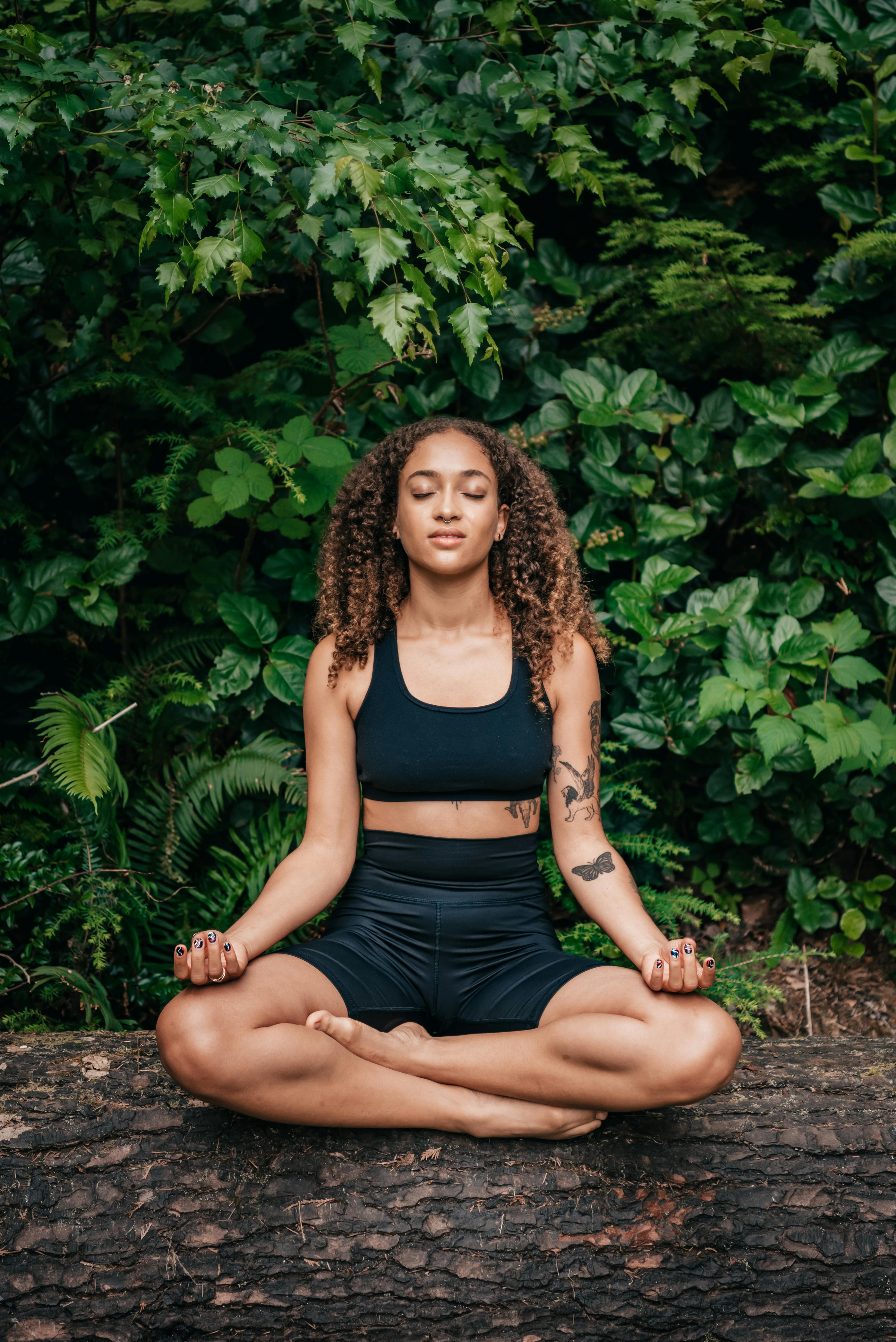 woman in black sports bra in lotus pose