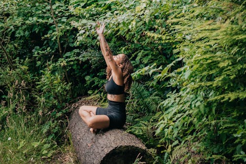 Free Woman in Black Activewear Sitting on a Tree Trunk Stock Photo