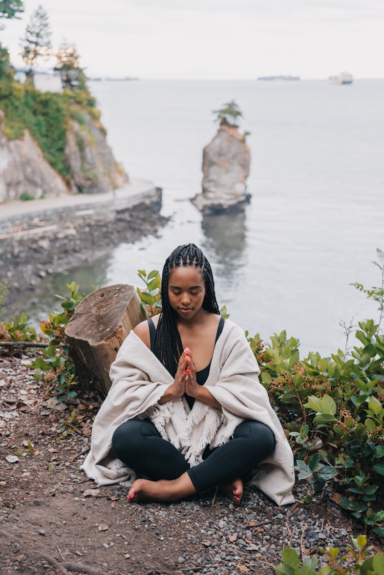 A Woman Doing Yoga Sitting On The Ground Beside The Sea 