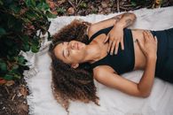 Woman in Black Activewear Lying Down on a White Cloth