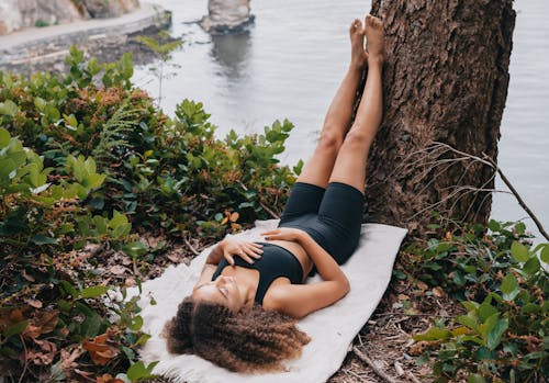 Free Woman in Black Activewear Lying Down on a White Cloth Stock Photo