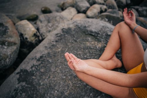 Free A woman in a meditative pose on a seaside rock, focusing on mindfulness and relaxation. Stock Photo
