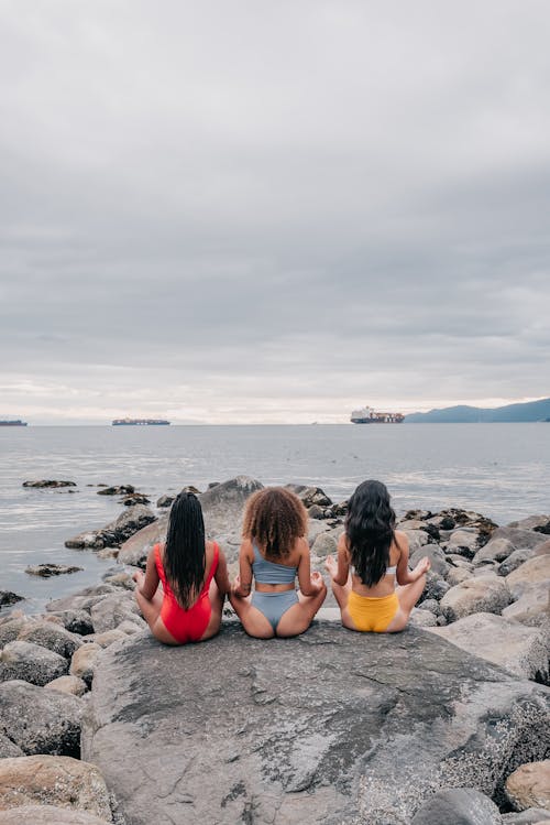 Free Women Sitting on a Big Rock while Meditating Stock Photo